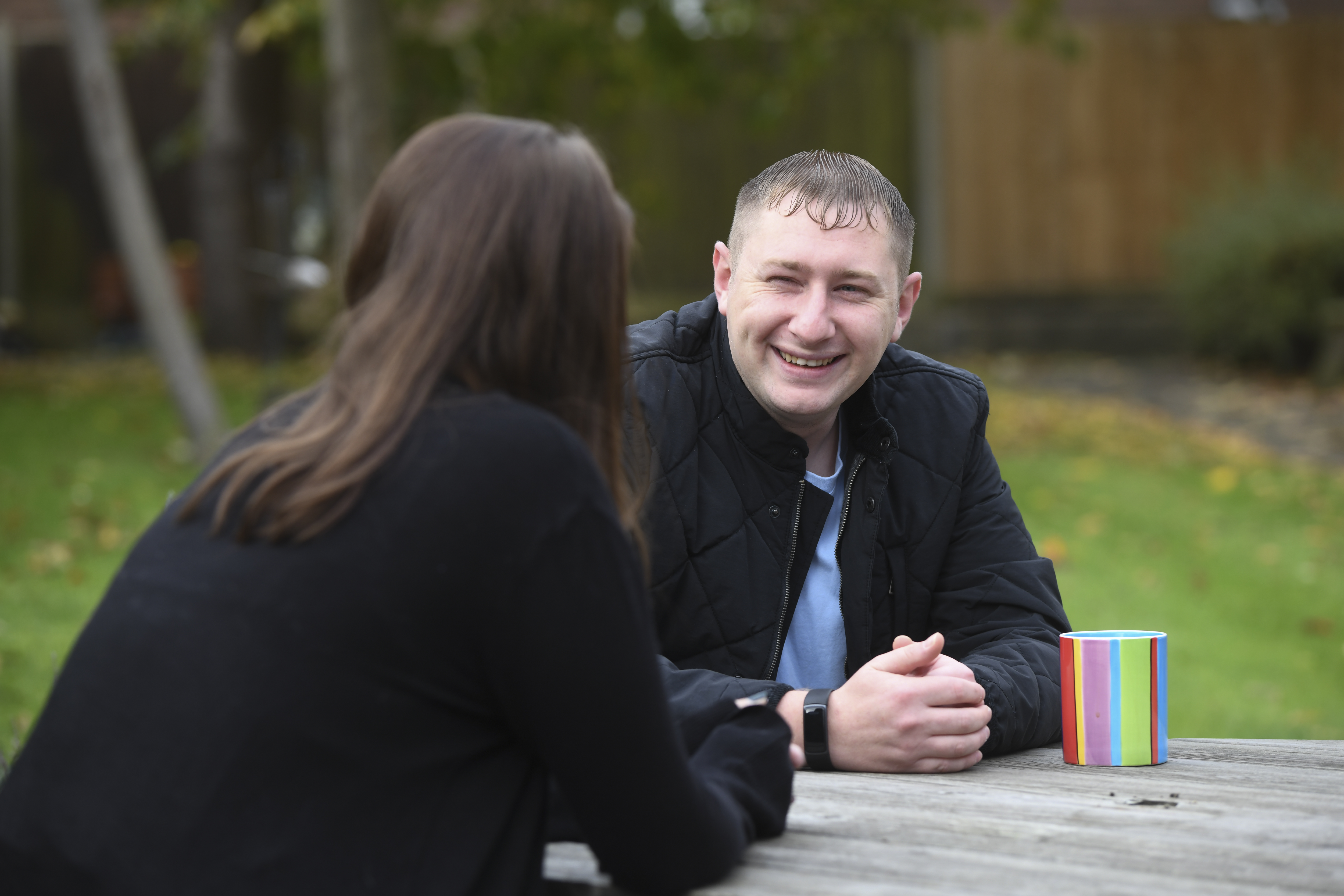 A male client in a garden at a table sitting opposite a Transform colleague
