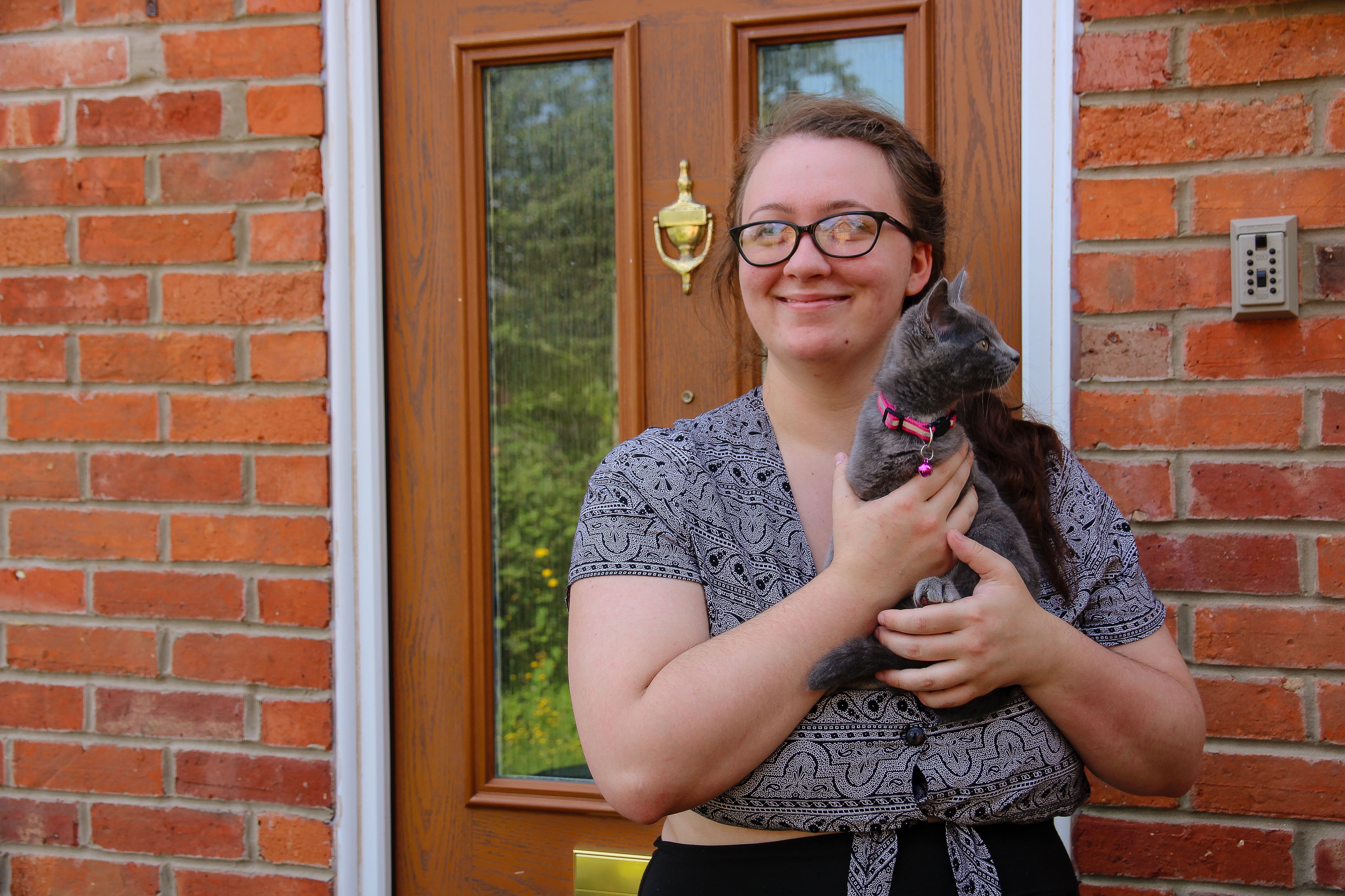 Female client holding a cat in front of a house door