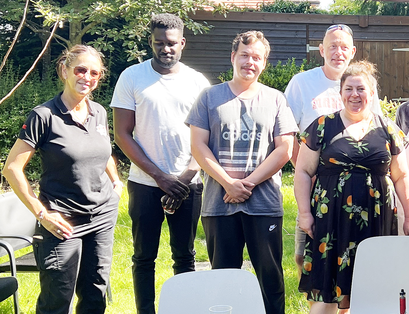 Three male clients and two female colleagues in a garden