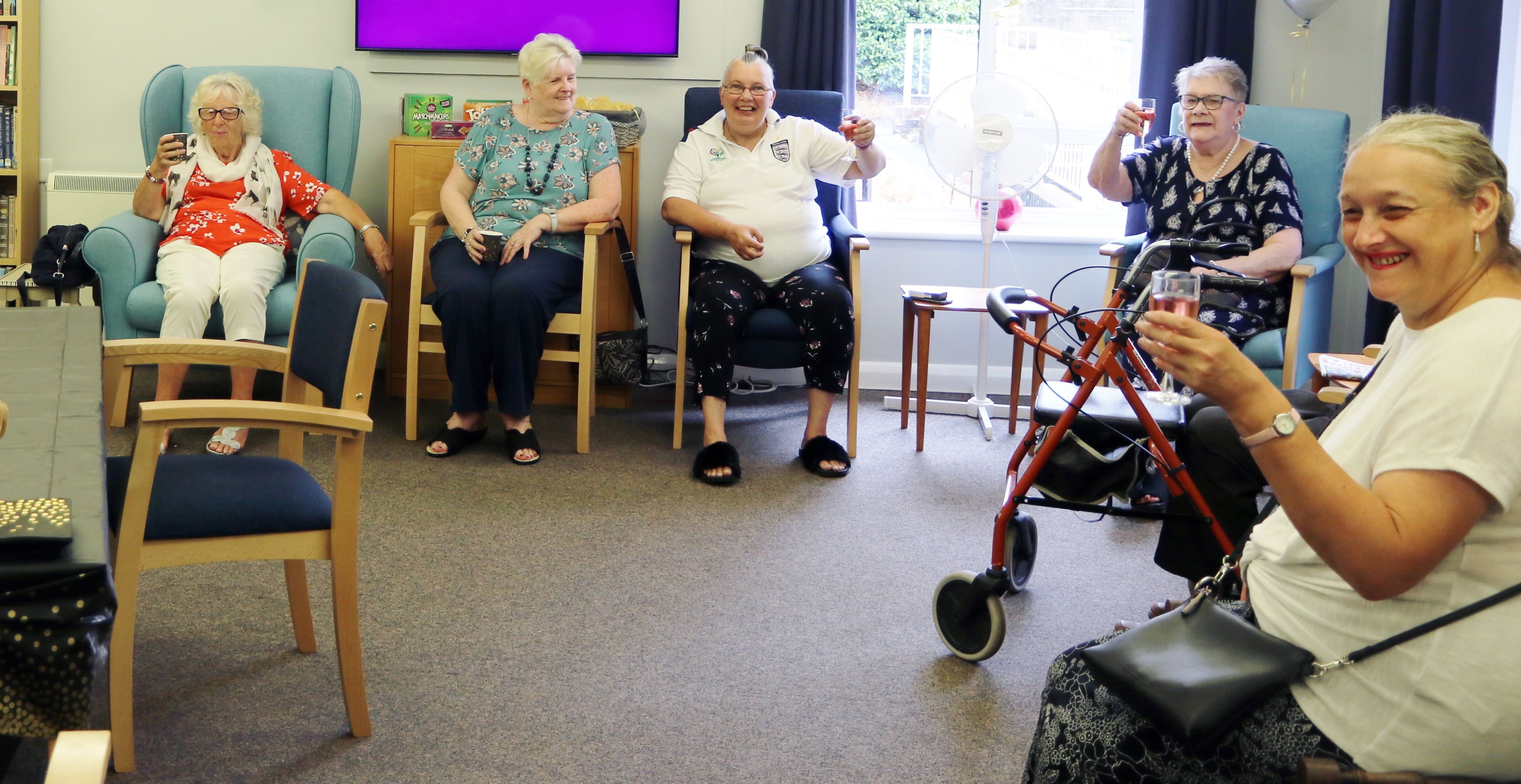 A group of older clients from our sheltered accommodation sitting a in a room with celebratory drinks